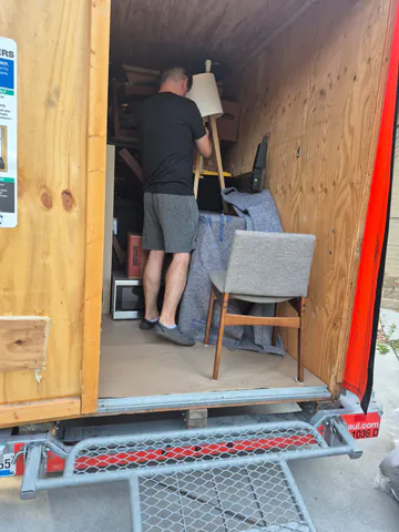 Mover positioning a floor lamp and protected furniture inside a moving container