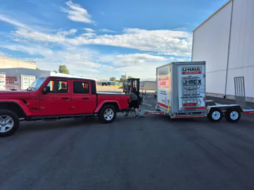 Customer vehicle positioned with a moving container trailer at a loading facility