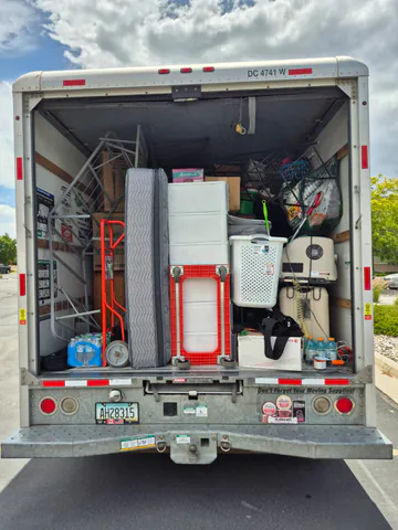 Moving truck packed with wrapped furniture, storage items, and moving equipment